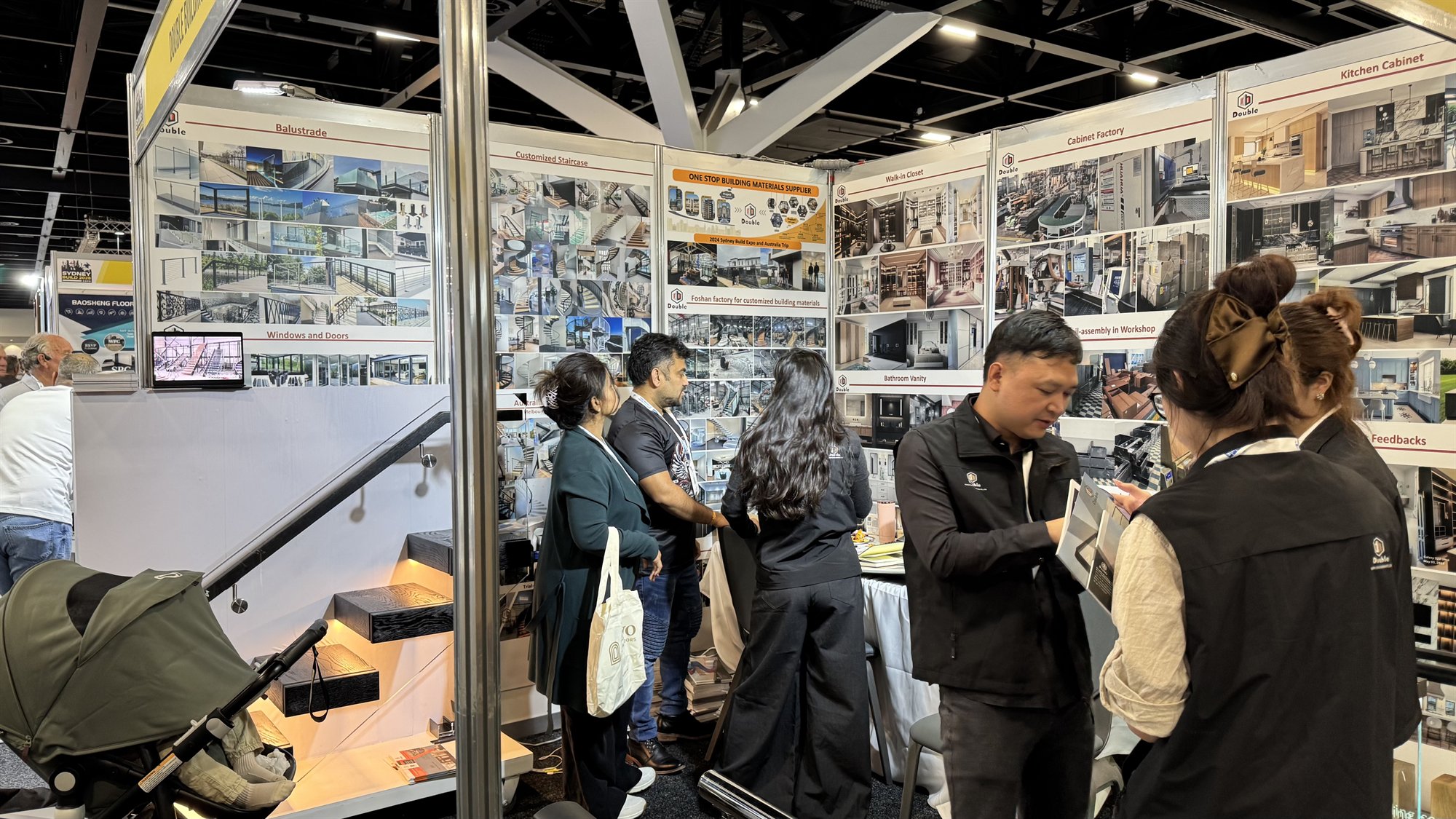 Visitors and the Double Building Materials team in conversation over catalogues at the Sydney Build 2026 stand