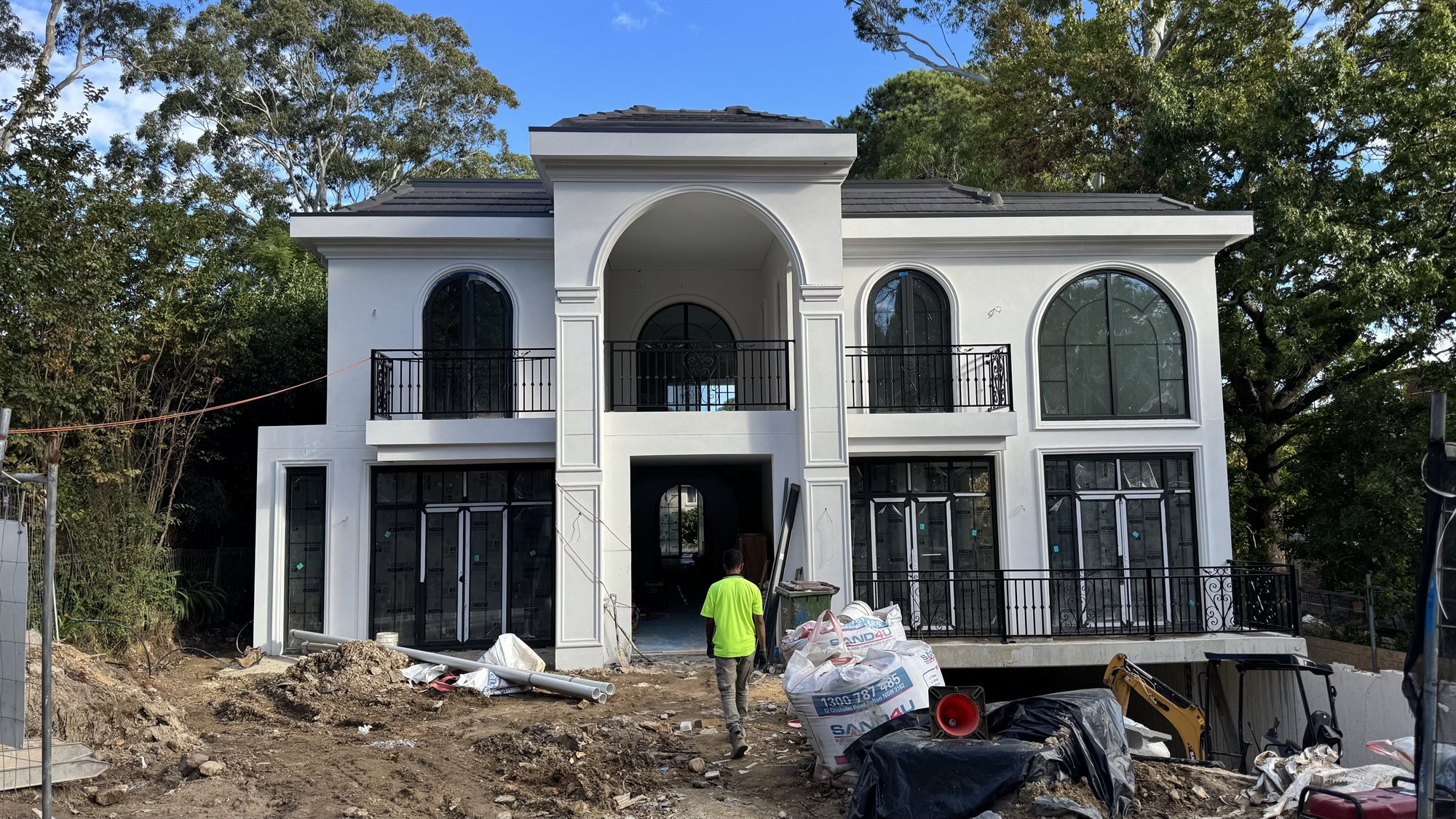 The exterior of a large white two-storey Sydney home under construction, with arched windows and a double-height portico