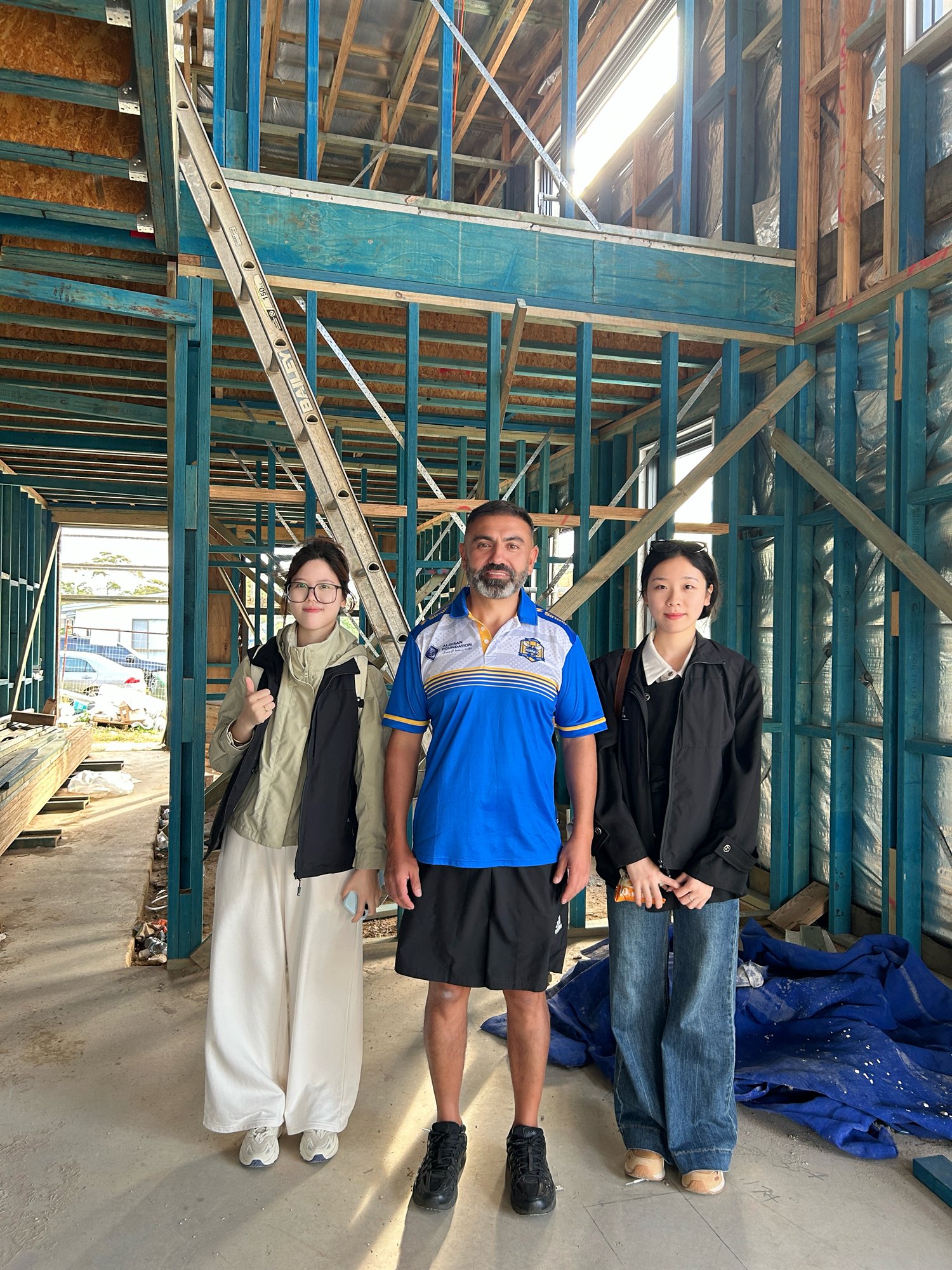 The Double Building Materials team with the owner inside a steel-and-timber framed Sydney home under construction, at the double-height void for the staircase