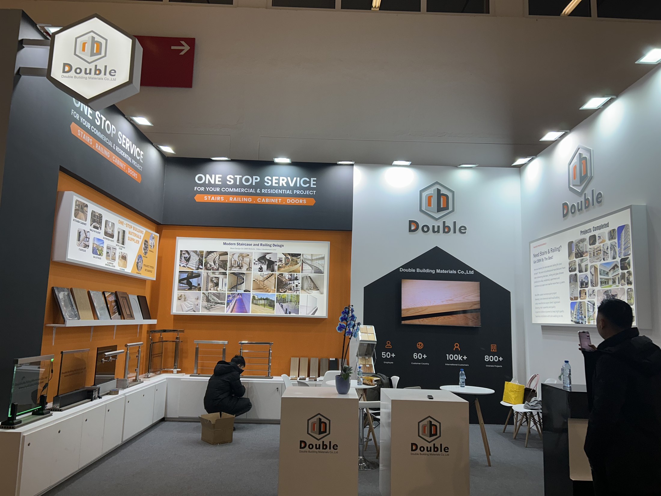 A wide view of the Double Building Materials stand at BAU 2025, with the one-stop-service banner, railing samples on white counters and the company hexagon sign