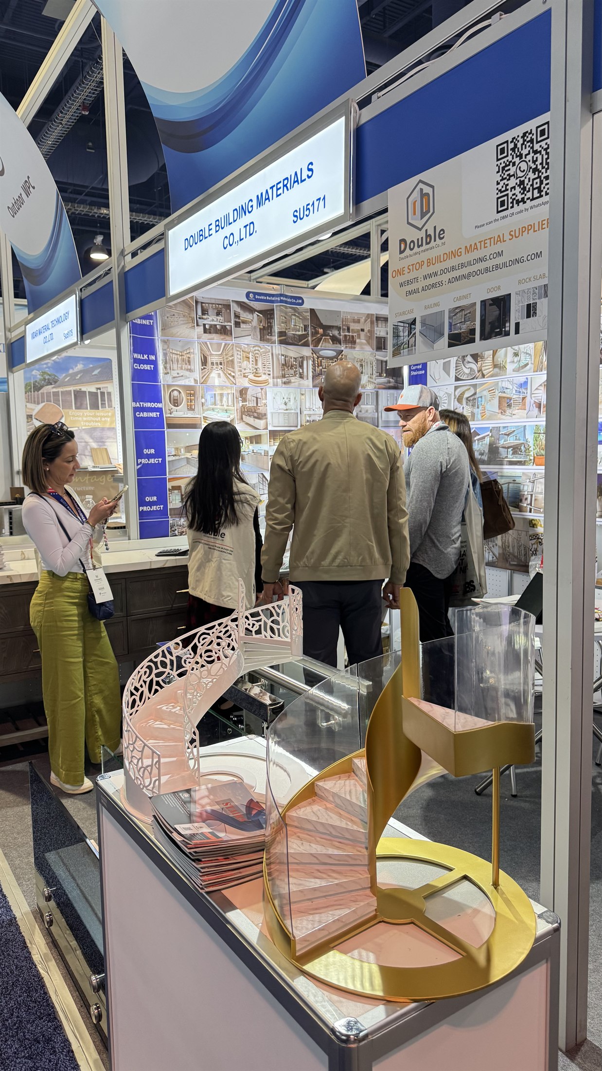 A gold spiral staircase scale model with a laser-cut filigree balustrade on the Double Building Materials stand at IBS 2025 in Las Vegas