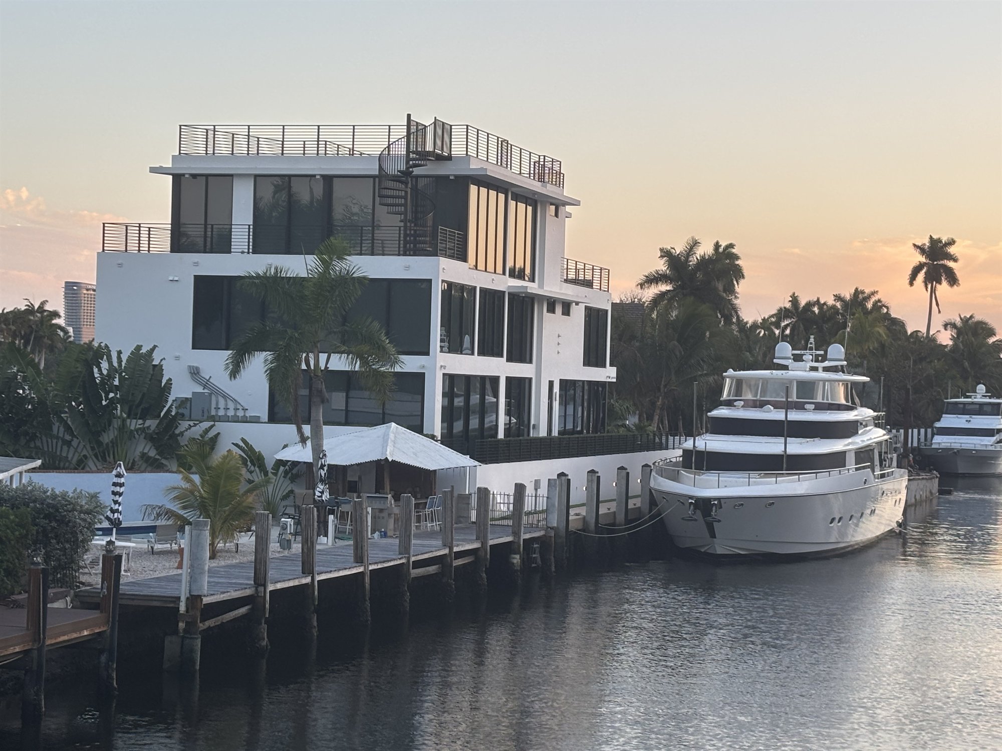 A modern white waterfront home on a Fort Lauderdale canal at dusk, one of the Florida client projects Double Building Materials visited after IBS 2026