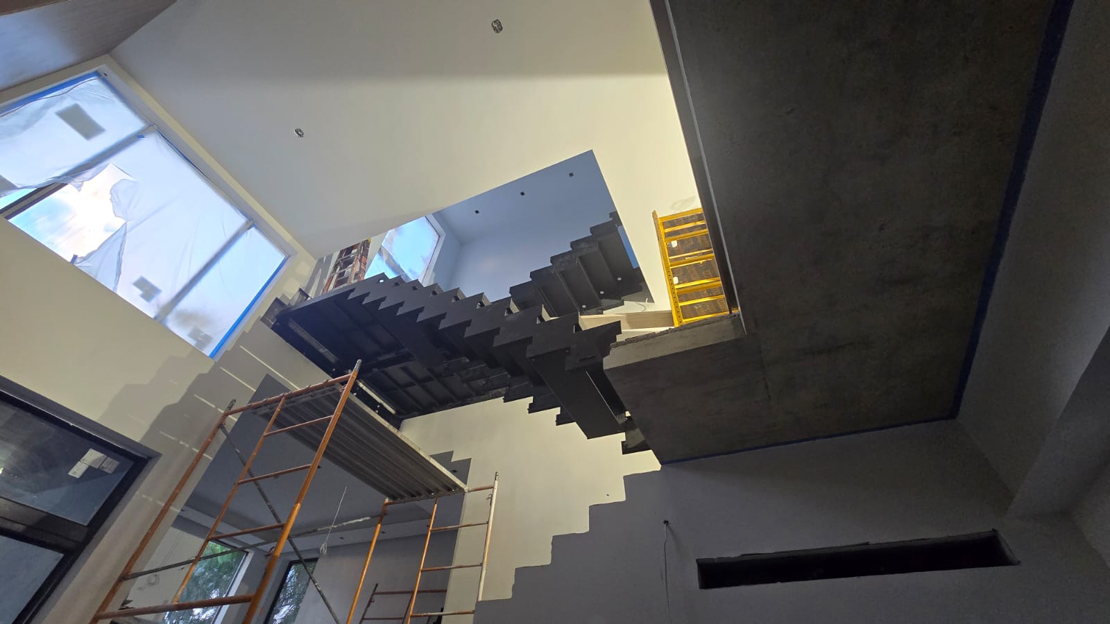 Black-steel floating staircase frame and cantilevered tread plates set out on site before the white oak is fitted, Florida