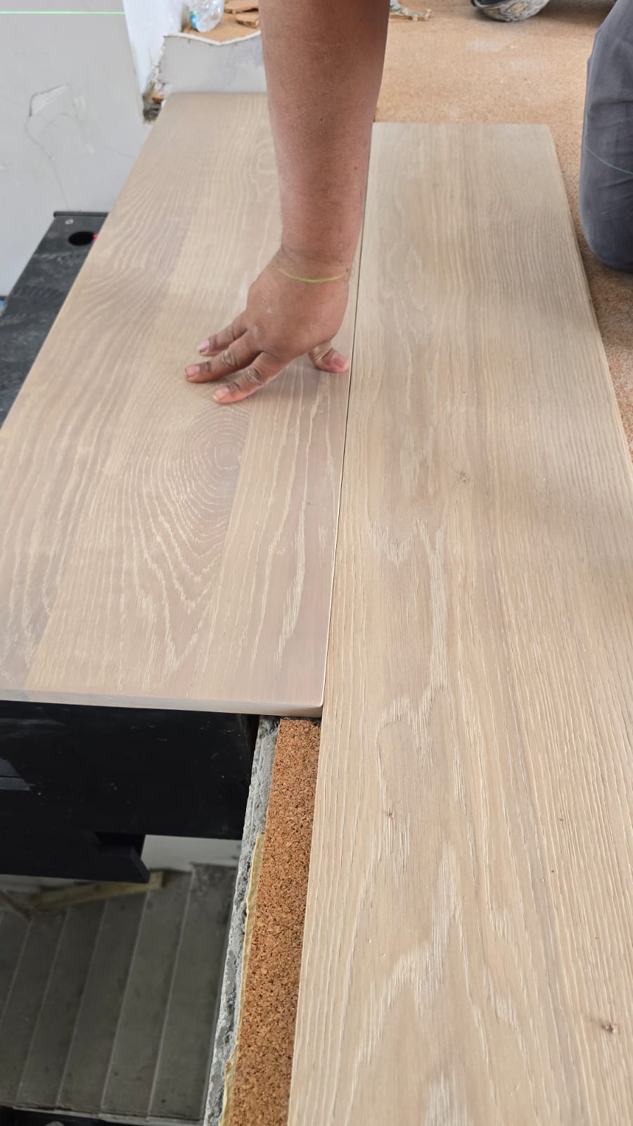 Two white-oak tread boards laid side by side for grain and color matching, with a worker's hand for scale, at the DBM workshop